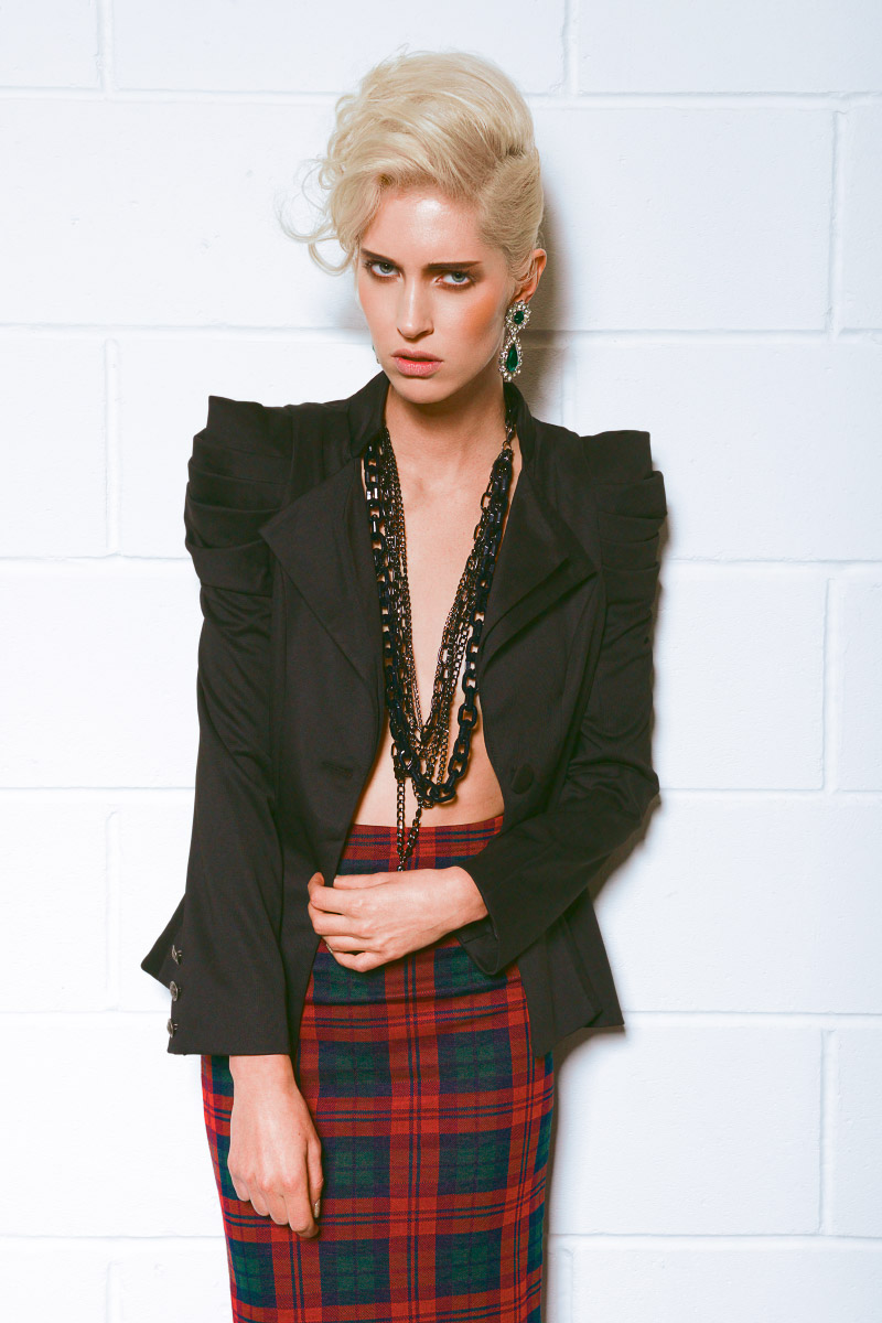 Fashion model wearing black jacket against a white wall